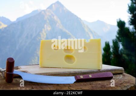 Käsesammlung, französischer emmental de savoie Käse mit runden Löchern, serviert im Freien in der Savoyer Region, mit Berggipfeln im Sommer auf dem Backgrou Stockfoto