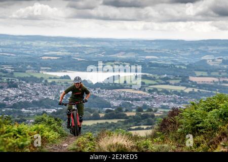 Eine Frau fährt mit dem Mountainbike bergauf auf auf einem Trail in den Hügeln über pontypool und Cwmbran in Torfaen, Wales. Stockfoto