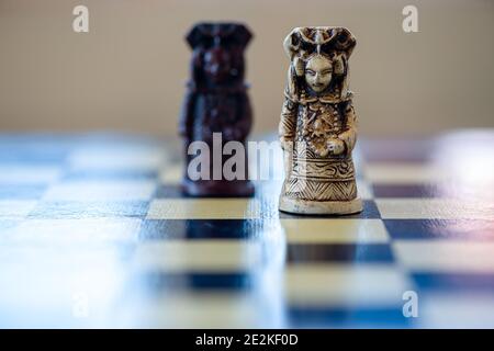 Nahaufnahme des schwarz-weißen Schachspiels der Königin, das auf einem Schachbrett sitzt. Schwarze Königin gegen weiße Königin. Stockfoto