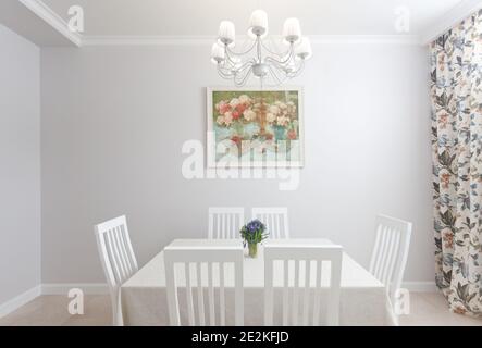 Foto von epmty minimalistischen Innenraum Hintergrund, Küche in moderner Wohnung mit großem Tisch, Stühlen, Blumen, Malerei, Kronleuchter und Vorhang, niemand Stockfoto