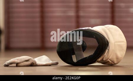 Eine Fechtmaske und ein Fechthandschuh auf dem Boden Stockfoto