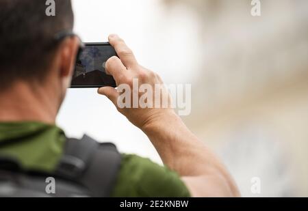 Thema Reisefotografie. Reisen kaukasischen Männer in seinen 30ern mit Rucksack nehmen Bilder mit seinem Smartphone. Stockfoto