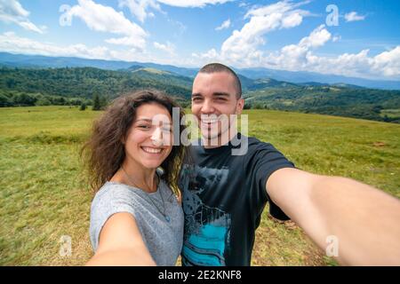 Junges Paar Umarmungen und Selfie mit erstaunlichen Berglandschaft Hintergrund. Stockfoto