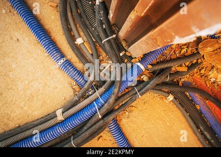 Komplizierte Elektrische Systeme. Viele verschiedene Kunststoff-Pipelines mit elektrischen Kabeln innen übereinander im neu gebauten Commercial B Stockfoto