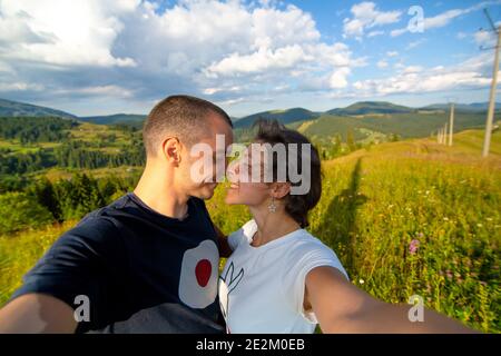 Junges Paar Umarmungen und Selfie mit erstaunlichen Berglandschaft Hintergrund. Stockfoto