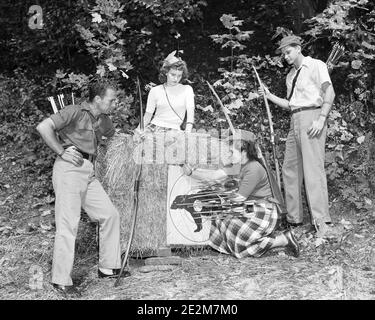 1950 ZWEI TEENAGER PAARE JUNGEN UND MÄDCHEN MIT BOGENSCHIESSEN BÖGEN PFEILE VOM ZIEL AUS BETRACHTEN UND ABRUFEN - A225 HAR002 HARS LIFESTYLE FRAUEN BRÜDER LÄNDLICHE KOPIE RAUM FREUNDSCHAFT GANZLÄNGE BOGENSCHIESSEN MÄNNER TEENAGER MÄDCHEN PFEIL TEENAGER JUNGE ATHLETISCHE GESCHWISTER VERTRAUEN SCHWESTERN S&W ZIELE ERFOLG AKTIVITÄT KÖRPERLICHE STÄRKUNG PFEILE ABENTEUER FREIZEIT SELBST. WERTSCHÄTZUNG AUFREGUNG ERHOLUNG ARCHER GELEGENHEIT GESCHWISTER BOGEN UND PFEIL MENTAL GESUNDHEIT VERBINDUNG BÖGEN FLEXIBILITÄT MUSKELN BOGENSCHÜTZEN JUGENDLICHE ENTSPANNUNG WIEDERGEWINNUNG ZWEISAMKEIT SCHWARZ UND WEISS KAUKASISCHEN ETHNIZITÄT ALTMODISCH Stockfoto