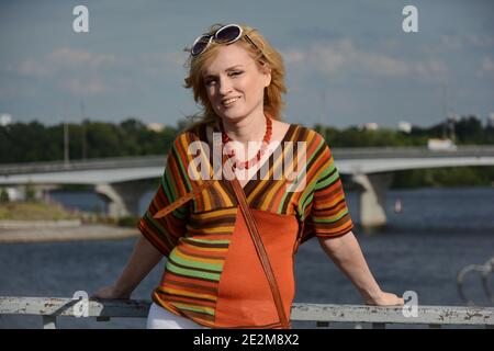 Eine Frau in 1970-Style Kleidung und Sonnenbrille lächelt im Freien Stockfoto