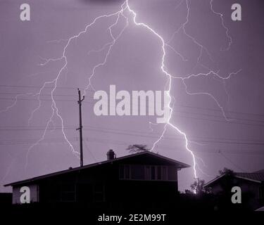 60S EINZIGEN BLITZSCHLAG ENTLADUNG IN HIMMEL ÜBER DUNKLEN WOHN VORSTADTVIERTEL HAUS WÄHREND DER NACHT ELEKTRISCHEN REGEN STURM - F11530 HAR001 HARS STORMY B&W NORTH AMERICA ENERGY NORTH AMERICAN NEIGHBORHOOD AUFREGUNG AUSSENBELEUCHTUNG NIEDRIGEN WINKEL STARKE SCHLAG IN DEN HÄUSERN KONZEPTIONELLE RESIDENZ GEWITTER SCHRAUBEN BLITZ HOCHSPANNUNG BLITZ STÜRME SCHLÄGT ENTLADUNG DER SCHWARZEN UND WEISSEN SCHRAUBE BEI ELEKTROSTATISCHER HAR001-METEOROLOGIE ALTMODISCHES PLASMA SCHWERER DONNER Stockfoto