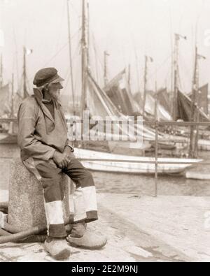 1920ER JAHRE ALTEN MANN FRANZÖSISCH FISCHER SITZEN AUF DOCK POLLER TRAGEN VON LOKALEN KOSTÜMEN UND HOLZSCHUHE CONCARNEAU BRETAGNE FRANKREICH - F3627 HAR001 HARS GESCHICHTE SEEMANN ÄLTERE JOBS FISCHER BOOTE NACH HAUSE LEBEN KOPIE RAUM IN VOLLER LÄNGE PERSONEN DOCK MÄNNER RUHESTAND SENIOR MAN TRANSPORT SENIOR ERWACHSENER EUROPA B & W HAFEN RENTNER SKILL BERUF FÄHIGKEITEN ALTER OLDSTERS OLDSTER EUROPÄISCHE SEGELBOOTE UND AUF LOKALEN BERUFEN ELDERS CLOGS ALTEN SALZ POLLER BRETAGNE CLOG SCHWARZ UND WEISS KAUKASISCHE ETHNIE FISCHEREI FLOTTE HAR001 ALTMODISCHE SEEMANN Stockfoto