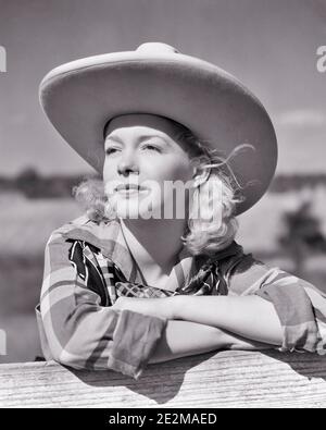 1940ER BLONDE COWGIRL TRÄGT GROSSE BRIMMED COWBOY HUT LEHNT AN ZAUN TRÄGT PLAID SHIRT BANDANA NACHDENKLICH GESICHTSAUSDRUCK - G3039 HAR001 HARS NORTH AMERICAN DREAMS GLÜCK KOPF UND SCHULTERN ABENTEUER COWGIRL REFLEKTIERENDE DENKEN STOLZ BERUFE REFLEKTIERENDE ERWÄGEN ERWÄGEN GALLON LOST IN THOUGHT CONCEPTUAL 10 STILVOLL KONTEMPLATIV MEDITIEREN MEDITATIV JUNG ERWACHSENE FRAU SCHWARZ UND WEISS KAUKASISCHEN ETHNIE IN ANBETRACHT HAR001 ALT FASHIONED RANCHER Stockfoto