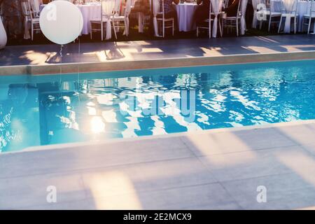 Wunderschöner Swimmingpool im Zentrum des Gartens, der für Hochzeiten dekoriert ist. Stockfoto