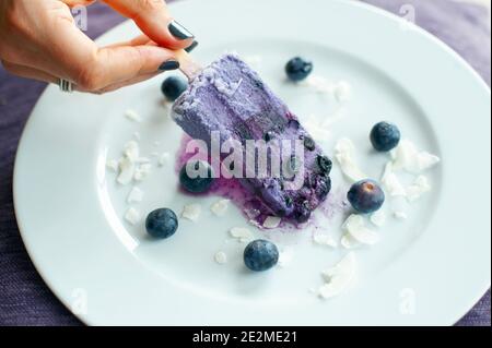 Draufsicht auf Frau Hand hält hausgemachte Heidelbeer-Eis. Gesunde Snacks ohne Gluten und Tagebuch Stockfoto