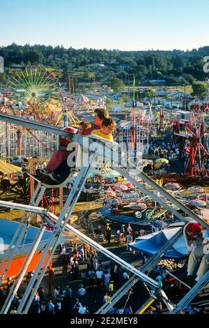 MUTTER UND ZWEI KINDER AUS DEN 70ER JAHREN REITEN AUF EINEM AUFREGENDEN RIESENRAD AUSSICHT AUF DEM LAND BIS HIN ZU VERGNÜGUNGSFAHRTEN UND MENSCHENMENGEN - KF12720 LGA001 HARS SCHWESTER 1 JUGENDANGST SICHERHEITSFAHRT SÖHNE FREUDE LIFESTYLE FRAUEN BRÜDER LÄNDLICHE KOPIE RAUM DAMEN TÖCHTER PERSONEN MÄNNER RISKIEREN ANGST KARNEVAL UNTERHALTUNG GESCHWISTER SCHWESTERN ANGST HOCH ANGLE ABENTEUER ÄNGSTLICH MUT ERHOLUNG GESCHWISTER KONZEPTUELL BEDROHT ÄNGSTLICH UNBESORGT KARNEVAL MESSEN SPANNENDE JUGENDLICHE MID-ADULT MID-ADULT FRAU MÜTTER REITET UNTERHALTUNG PARK KAUKASISCHE ETHNIE ALTMODISCHEN THEMENPARK Stockfoto