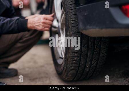 Auto Mechaniker mit elektrischem Schraubendreher Reifen aussen wechseln. Autoservice. Reifenmontage. Stockfoto