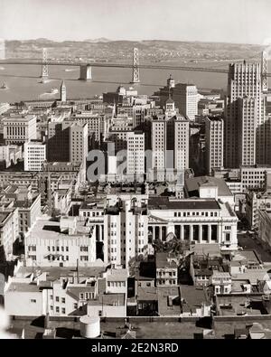 GEBÄUDE IM STADTZENTRUM DER 1930ER JAHRE MIT DEM WESTLICHEN TEIL VON OAKLAND BAY BRIDGE IM HINTERGRUND SAN FRANCISCO CALIFORNIA USA - Q39320 CPC001 HARS BRÜCKEN VERBINDEN ALTMODISCHE ABSCHNITT AUFHÄNGUNGSTÜRME Stockfoto