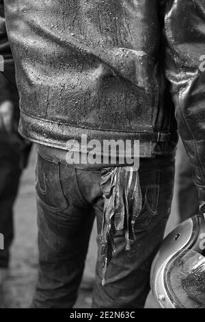 Rückansicht des Mannes mit Lederjacke, Jeans mit Rückentasche und Motorradhelm. Stockfoto