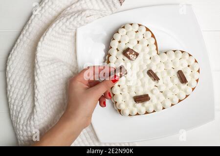 Schritt-für-Schritt-Rezept für herzförmige Kuchen. Schritt 12: Den Kuchen mit Schokoladenstückchen, Waffeln, Keksen dekorieren. Flach liegend. Stockfoto