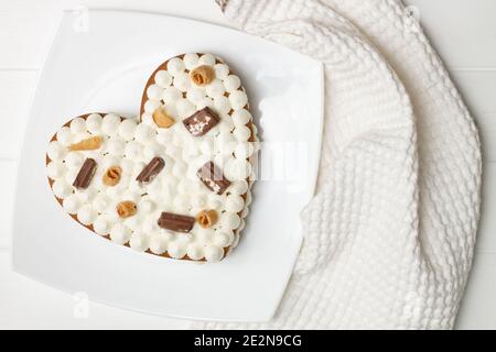 Schritt-für-Schritt-Rezept für herzförmige Kuchen. Schritt 12: Den Kuchen mit Schokoladenstückchen, Waffeln, Keksen dekorieren. Flach liegend. Stockfoto