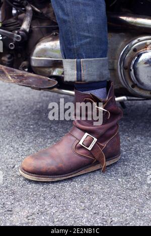 Nahaufnahme von jungen Männern in Jeans und Stiefeln Posiert auf dem Motorrad Stockfoto