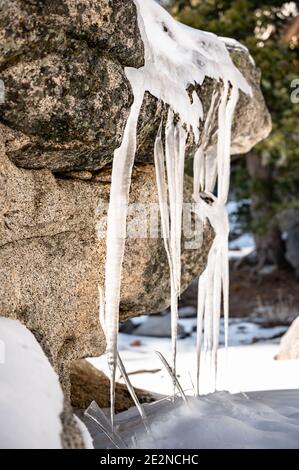 Eiszapfen bildeten sich im frühen Winter auf einem Felsen Stockfoto