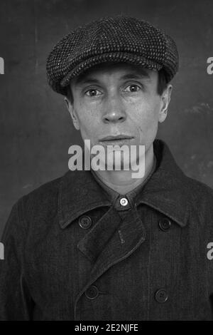 Nahaufnahme, schwarz-weiß, Vorderansicht Porträt eines isolierten Mannes mit flacher Mütze und Denim-Mantel, London, England. Stockfoto