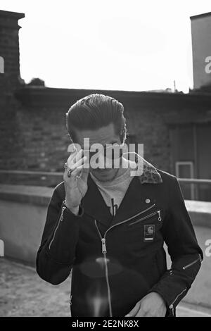 Stilvoller Rocker mit Lederjacke und Sonnenbrille auf dem Dach von London Stockfoto