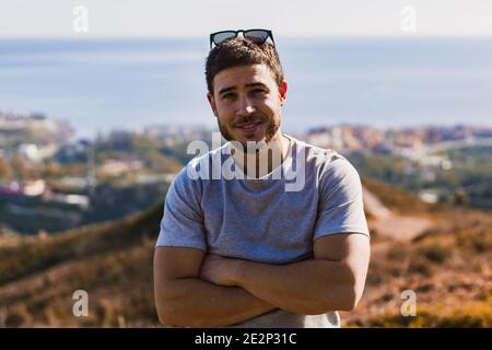 Porträt des jungen Mannes mit Sonnenbrille auf dem Kopf mit Landschaft Im Hintergrund Stockfoto