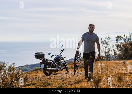 Biker mit Zangen für sein zerbrochenes Motorrad Stockfoto