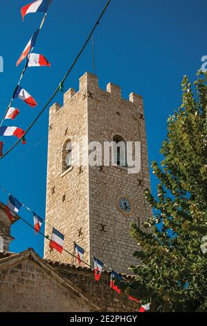 Blick auf Steinturm neben Kirche und Fahnen in Vence, einem atemberaubenden mittelalterlichen Weiler komplett erhalten. Region Provence, südöstliches Frankreich. Stockfoto