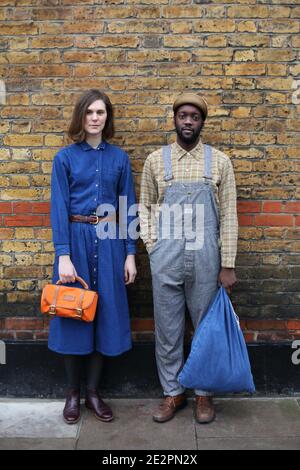 Multirassische stilvolle Paar in Denim-Kleidung posiert auf einem Hintergrund einer Ziegelwand. Schwarz afrikanischen britischen Mann und kaukasischen Frau Datum und Liebe. Stockfoto