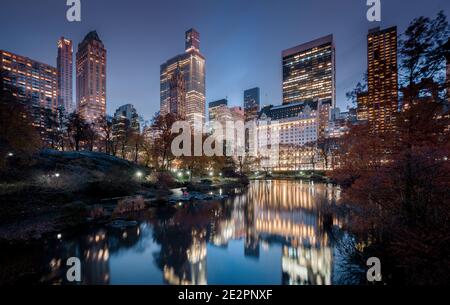 New York City Midtown Skyline spiegelt sich im Teich am Central Park South von der Gapstow Bridge während der blauen Stunde in der Dämmerung, New York, USA Stockfoto