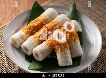 Japanische Chikuwa serviert auf einem weißen Teller auf einem hölzernen Hintergrund Stockfoto