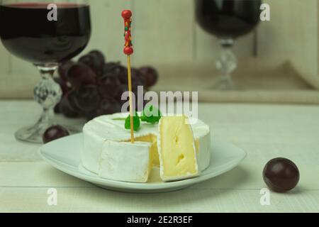 Foto mit zwei Gläsern Rotwein und Käse mit Trauben auf einem Holzbrett. Runden Camembert Käse und Trauben mit Rotwein Stockfoto