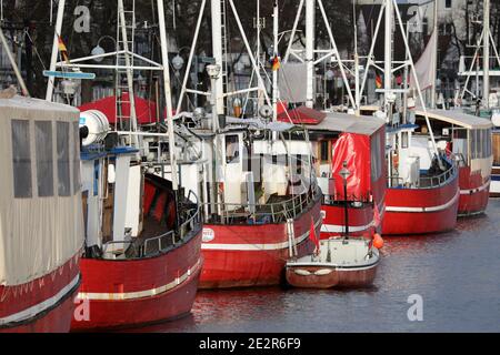 13. Januar 2021, Mecklenburg-Vorpommern, Warnemünde: Die roten Angelscheren, ehemalige Fischerboote, werden zusammen mit Fischverkuttern am Alten Strom des Ostseebades vertäut. Die Fischkutter - wie die Passagierschiffe - dürfen aufgrund der Corona-Vorschriften nicht mit Passagieren segeln. Die Corona staatliche Verordnung verbietet das Angebot von Angeltouren mit Kutter und kommerzielle Vermietung Boote. Foto: Bernd Wüstneck/dpa-Zentralbild/dpa Stockfoto