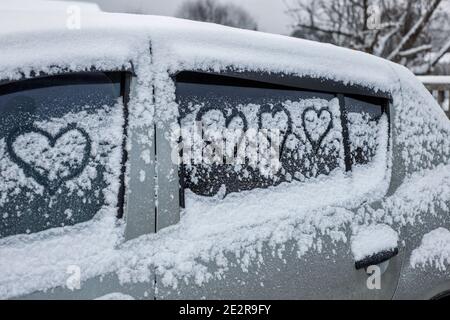 Herzen sind auf Glas in schneebedeckten Auto gemalt. Selektiver Fokus Stockfoto