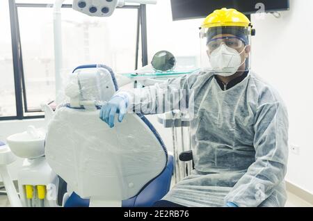 Porträt eines peruanischen jungen Zahnarztes mit Maske und Visier in einer Zahnarztpraxis. COVID - 19 Virenschutz Stockfoto