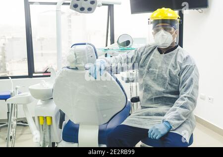 Porträt eines peruanischen jungen Zahnarztes mit Maske und Visier in einer Zahnarztpraxis. COVID - 19 Virenschutz Stockfoto