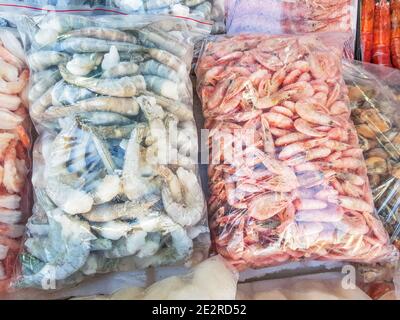 Zwei große Plastiktüten mit gefrorenen rohen und gekochten Garnelen, auf der Theke des Fischmarktes. Stockfoto