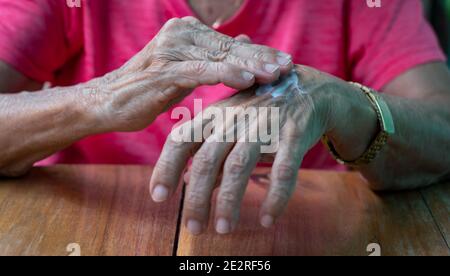 Faltige Hände, die Creme auf die Haut auftragen Stockfoto