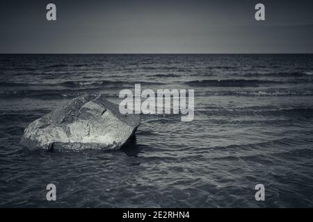 Stein liegt auf einem Meeresboden in seichtem Wasser, Ostsee Küstenlandschaft, blau getönte monochrome Foto Stockfoto