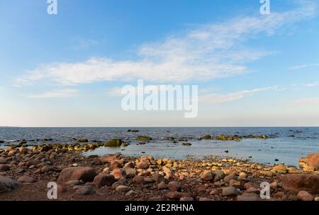Ostsee Felsküste im Sommer. Landschaftsfoto mit Uferwasser und Steinen unter wolkenblauem Himmel Stockfoto