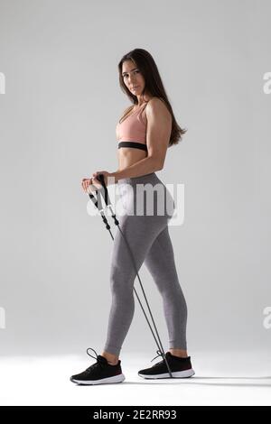 Frau in Sportswear macht Übungen mit Expander, junge Frau macht Fitness mit Expander auf weißem Hintergrund Stockfoto