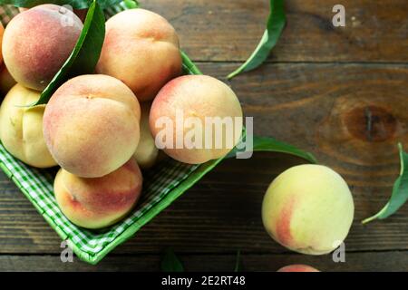 Reife Pfirsiche im Korb auf Holzhintergrund. Hausernte aus dem eigenen Garten. Gesunde Ernährung. Stockfoto