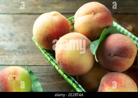 Reife Pfirsiche im Korb auf Holzhintergrund. Hausernte aus dem eigenen Garten. Gesunde Ernährung. Stockfoto