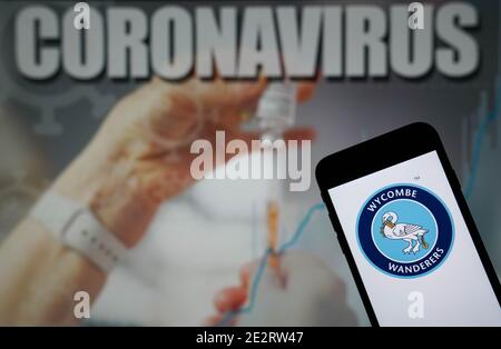 Datei Foto vom 09-01-2021 des Wycombe Wanderers Football Club Logo, das auf einem Mobiltelefon mit einem Coronavirus angezeigt wird Abbildung auf einem Monitor im Hintergrund Stockfoto