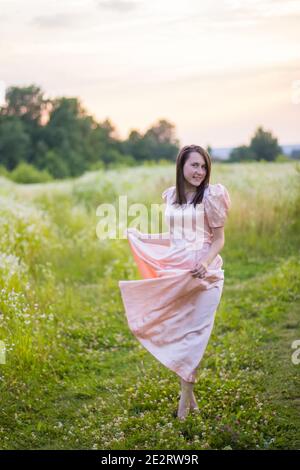 Mädchen tanzen auf dem Feld in einem rosa Kleid Stockfoto