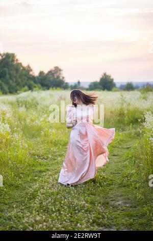 Mädchen tanzen auf dem Feld in einem rosa Kleid Stockfoto