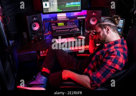 Foto von Audio-Ingenieur arbeiten in Musikaufnahme Studio, nutzt Mischpult schaffen modernen Sound. Erfolgreicher Künstlermusiker, der am Kontrollpult arbeitet. Stockfoto