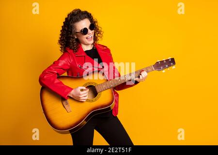 Portrait von ziemlich fröhlich talentiert berühmten wellig-haarigen Mädchen Gitarre spielen Isoliert auf hellgelbem Hintergrund Stockfoto