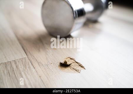 Loch In Laminatboden Von Gefallener Hantel Stockfoto